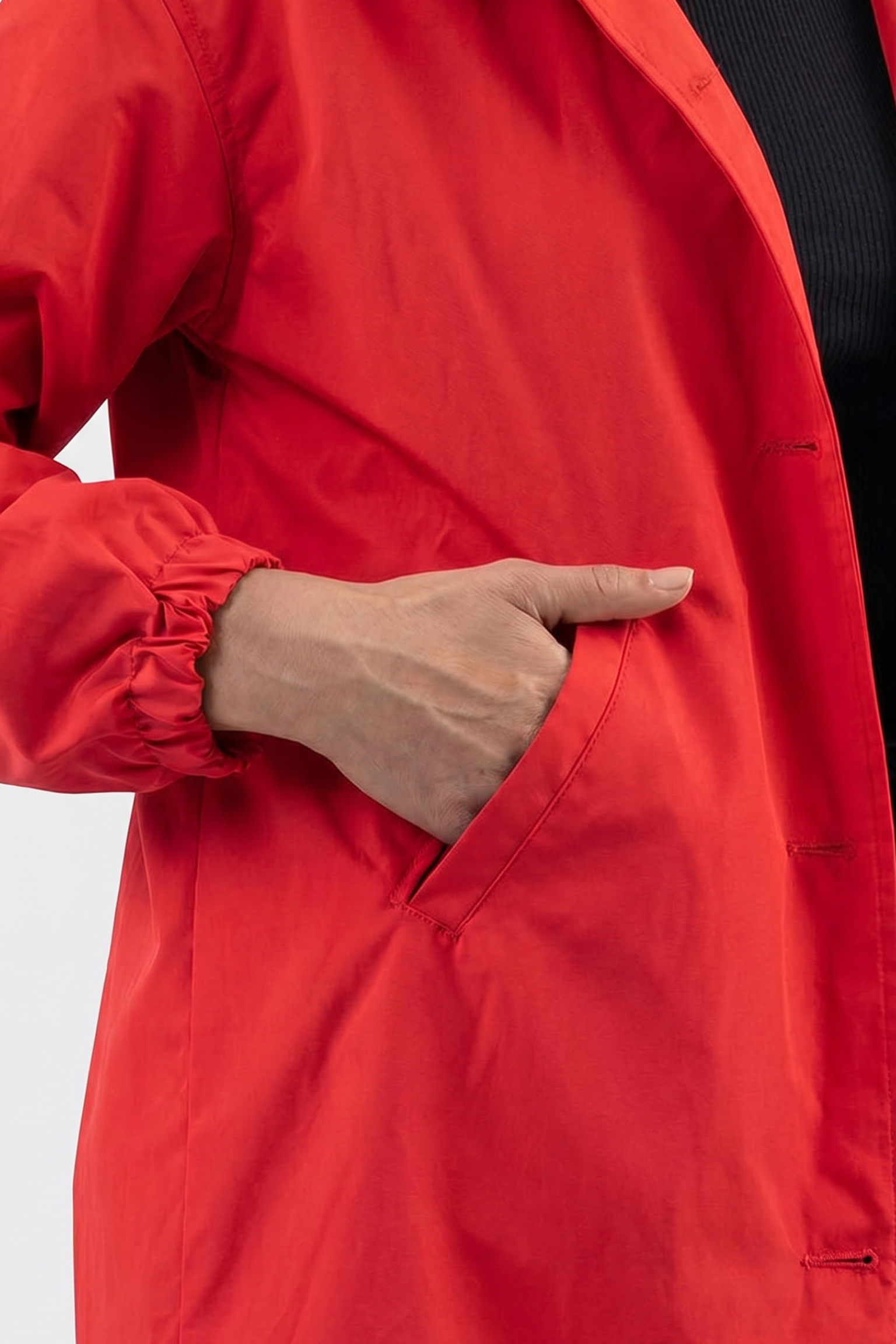 A person wearing the Icon Windbreaker Rain Jacket with elasticated sleeves has their hand partially inside a side pocket, set against a plain, light-colored background.