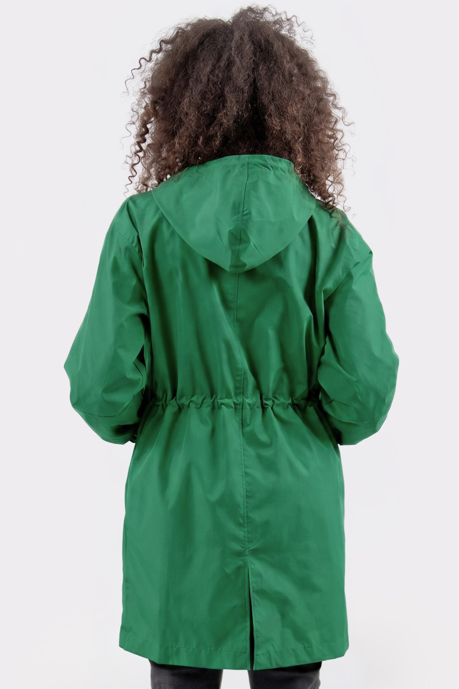 A person with curly hair is seen from the back wearing the Icon Windbreaker Rain Jacket in green, featuring a hood and drawstring waist, standing against a plain white background.