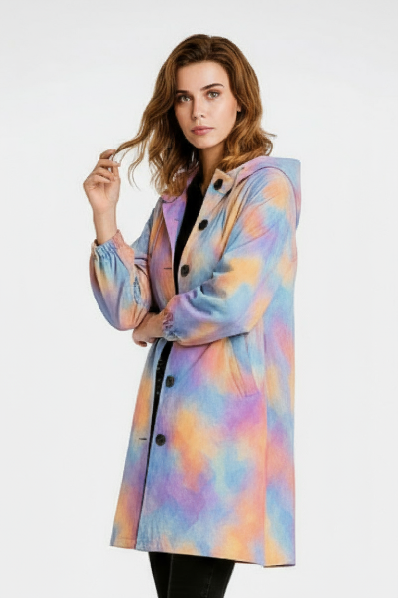 A person with shoulder-length hair wears the looselyboho CANVAS SKY WINDBREAKER in pastel tie-dye with black buttons over black pants, standing against a plain white background.
