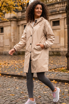 Someone wearing the Icon Windbreaker Rain Jacket walks along a cobblestone path with fallen leaves, surrounded by stone buildings and autumn trees.