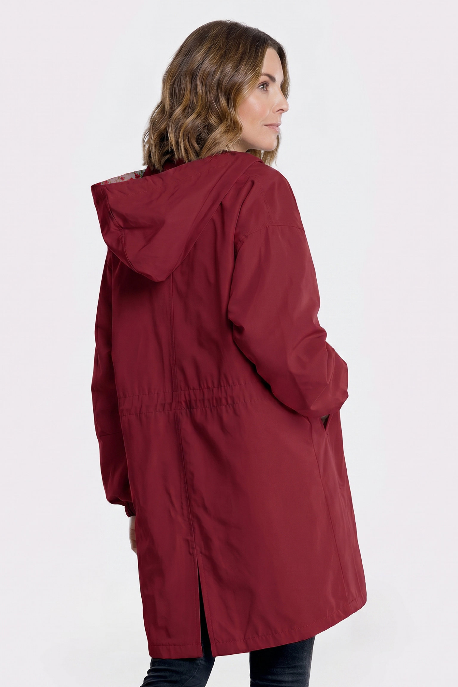 A person with light brown, wavy hair is seen from behind wearing The Water Resistant Hooded Oversized Windbreaker Rain Jacket in maroon, against a plain light background.