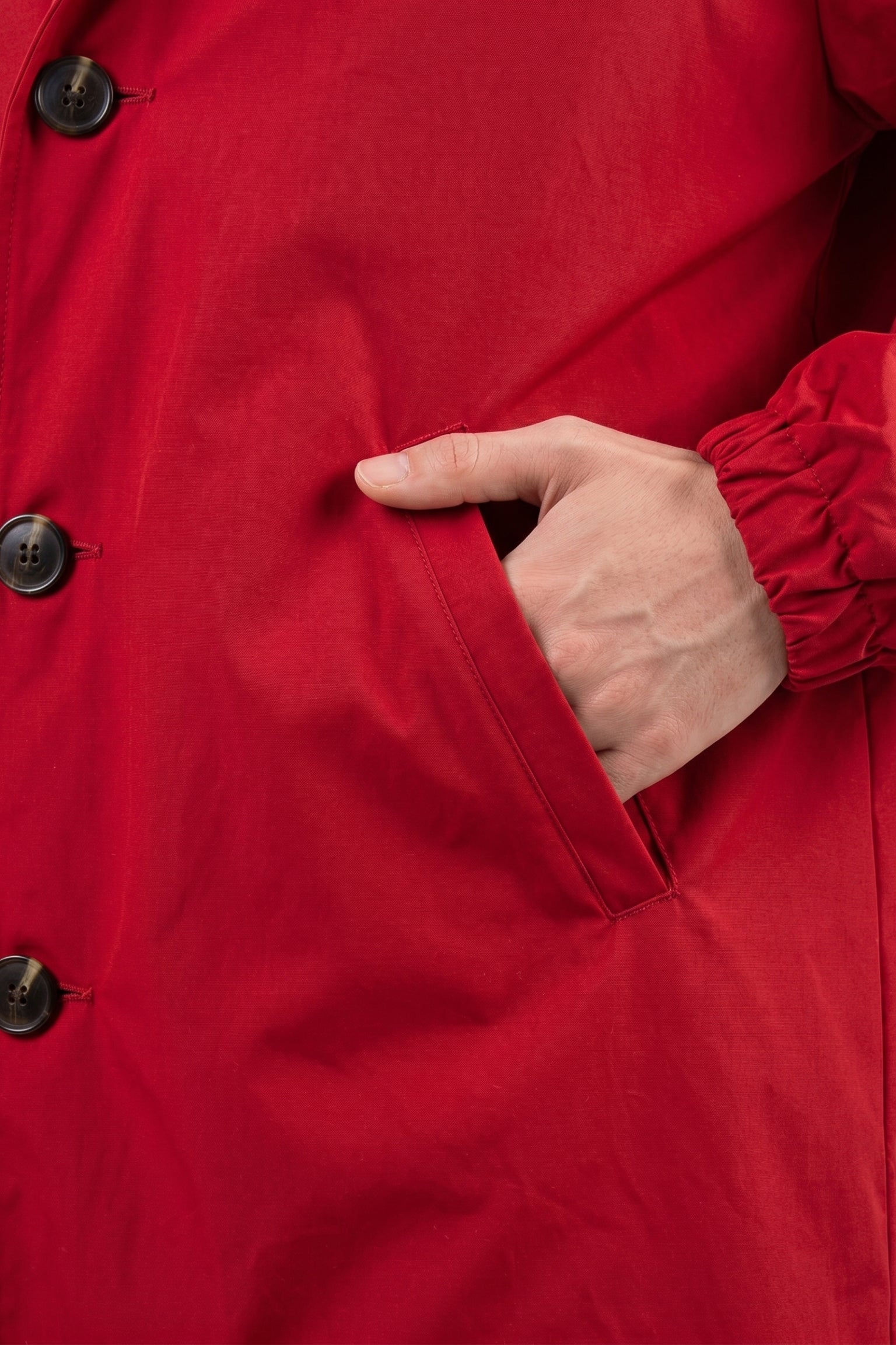 A person wearing the Icon Windbreaker Rain Jacket places their right hand in the jacket pocket, showing only the hand, pocket, and part of the front of the jacket.