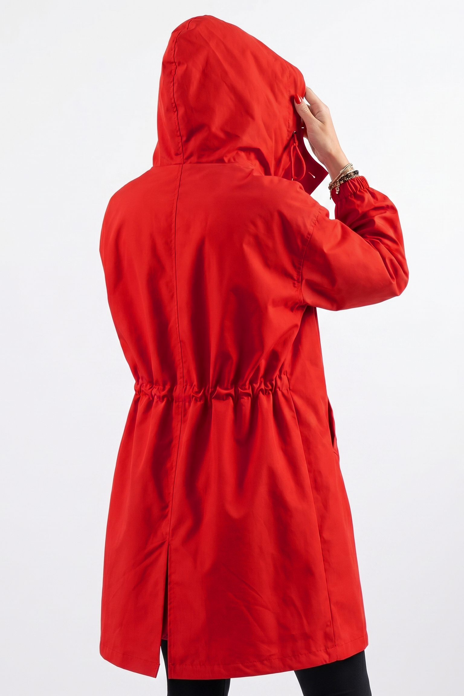 A person wears the Icon Windbreaker Rain Jacket in vibrant red, facing away while holding the hood. This jacket includes an elastic waist and a back hem slit for style and comfort.