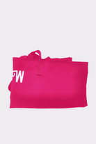 The Urban Slate Waterproof Bag, a bright pink rectangular gym and travel bag with short handles, is laid flat on a light gray background. The partial white "MW" letters appear on the left side of the bag.