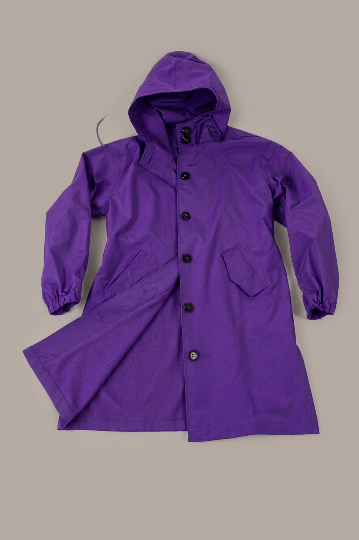Sure! Here is your rewritten sentence using the given product data: A long-sleeved, hooded purple Icon Rain Windbreaker Jacket featuring black buttons, two front pockets, and an open lower front, displayed on a plain light brown background.
