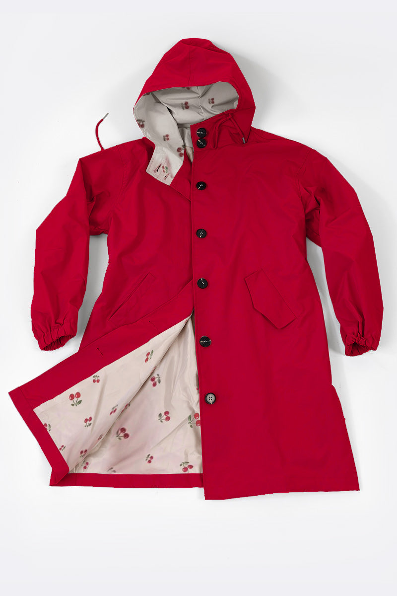 The CHERRY RED WINDBREAKER by looselyboho, crafted from water-resistant material, is displayed against a white background. The windbreaker is open, showcasing its white inner lining with a subtle cherry pattern. It features a button-down front, two front pockets, and elastic cuffs.